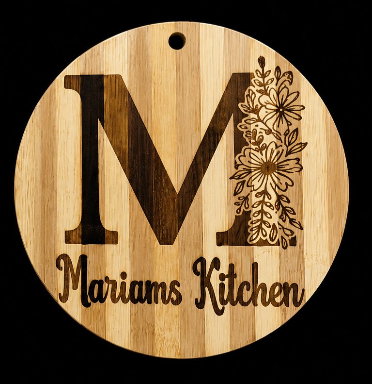 Round engraved wooden board with floral monogram M reading Mariams Kitchen