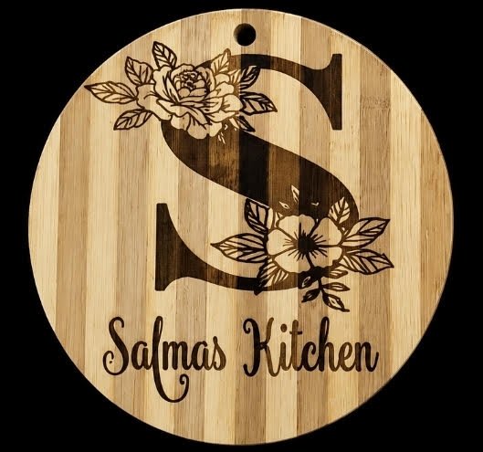 Round engraved wooden board with floral monogram S reading Salma's Kitchen